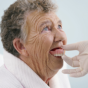 Orthodontist checking up old woman's dentures Skopek Orthodontics